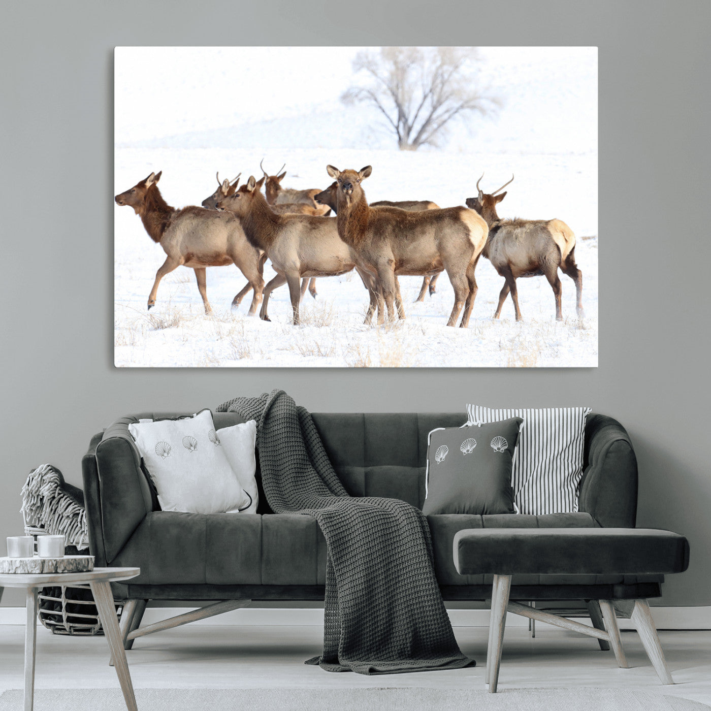 A group of elk standing on snowy terrain with a tree in the background, perfect for rustic or lodge-style winter wall decor.