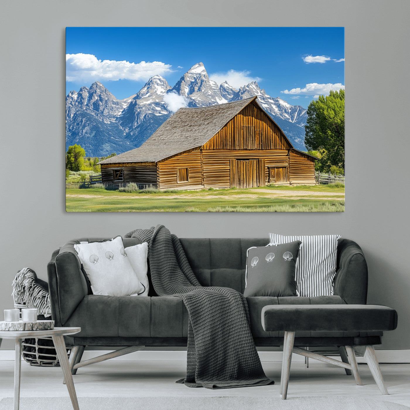 A rustic wooden barn sits in front of towering mountain peaks under a clear blue sky, perfect for farmhouse or cabin style interiors.