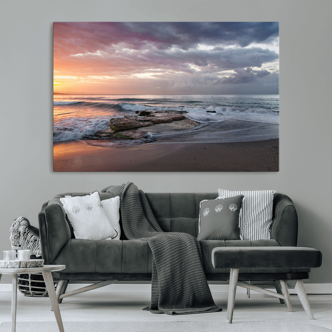 Dramatic sunset over a rocky shoreline with ocean waves gently reaching the sandy beach, creating a serene and coastal atmosphere.