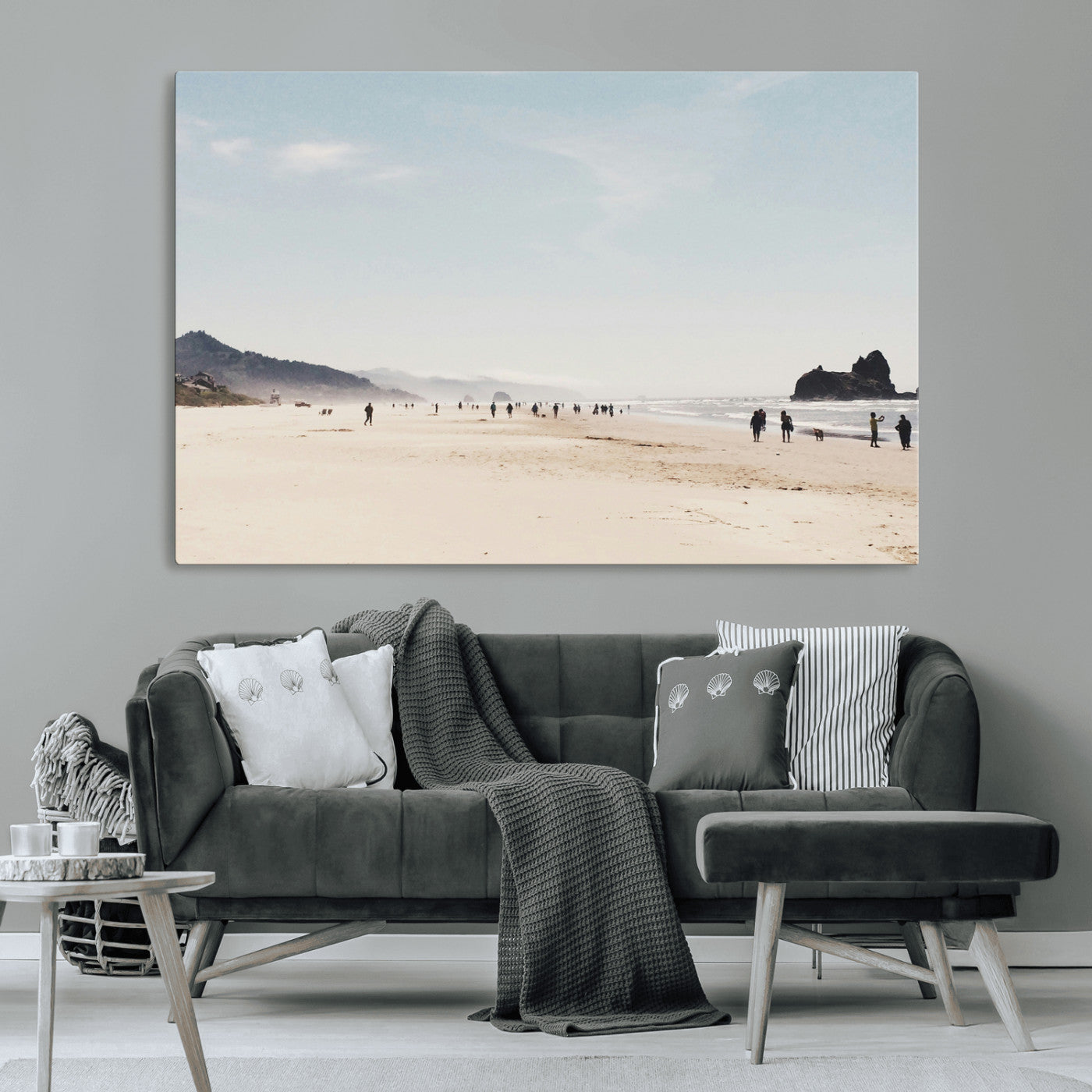 A serene beach with soft sand, misty mountains, and scattered people walking along the shoreline, creating a peaceful coastal landscape.