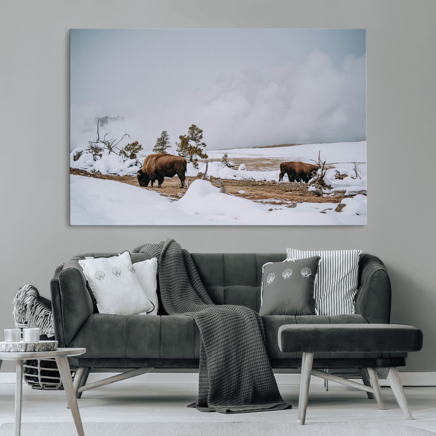 Two bison grazing in a snowy open landscape with misty hills in the background, creating a peaceful and rustic winter scene.