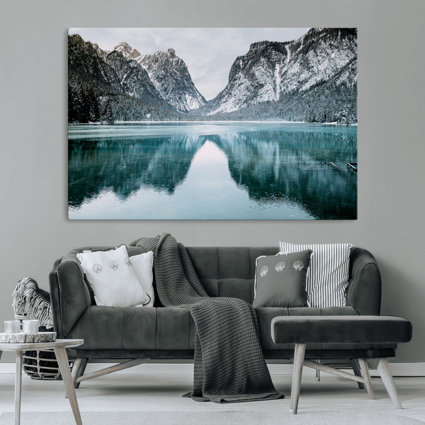 Crystal-clear alpine lake reflecting snow-covered mountains, surrounded by evergreen trees, creating a serene and tranquil winter landscape.