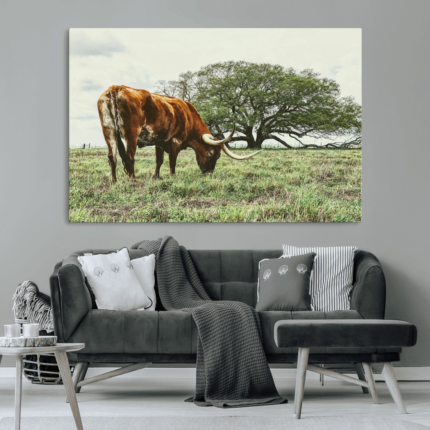 A Texas Longhorn grazing in a green pasture with a large tree in the background, evoking a rustic Western and farmhouse aesthetic.