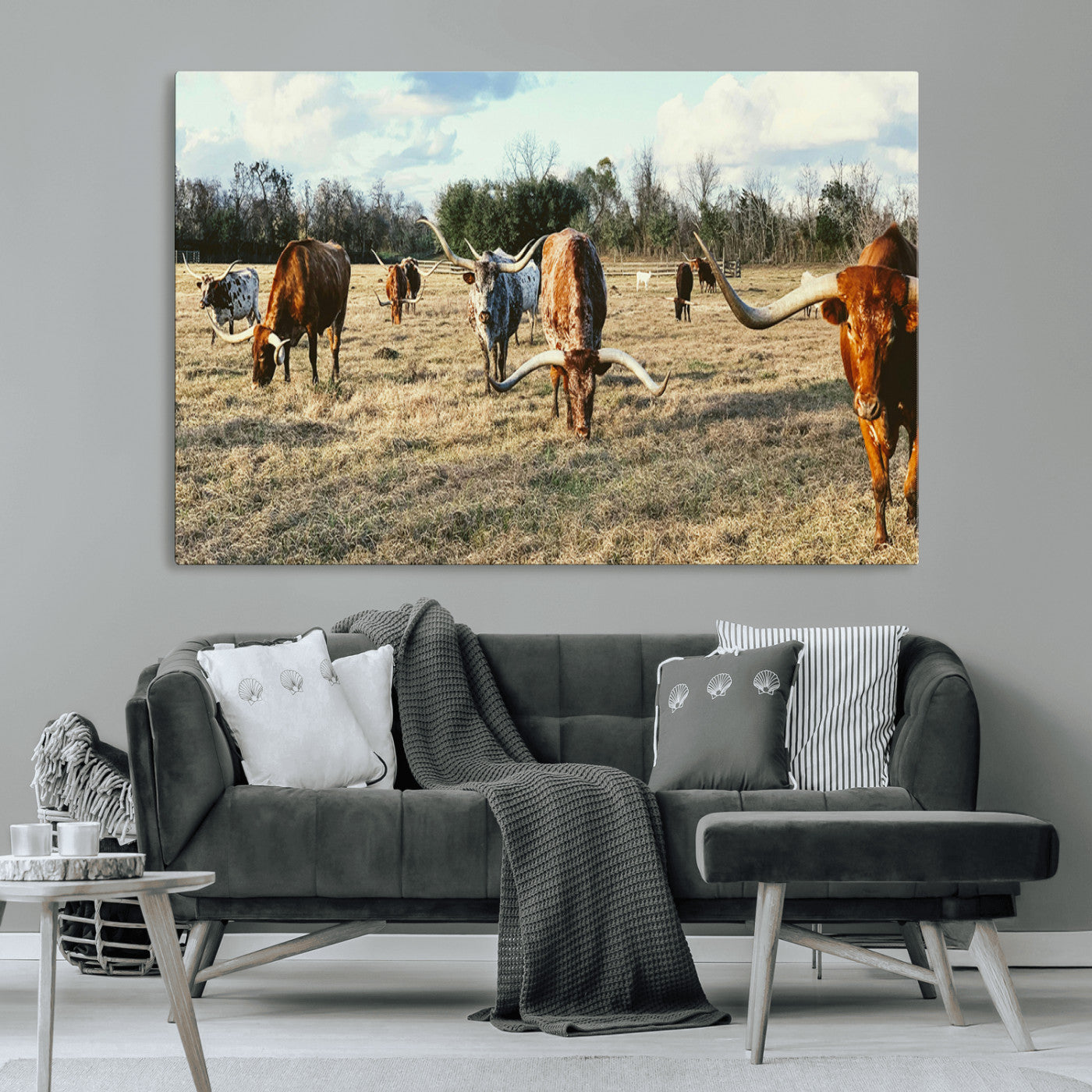 A herd of Texas Longhorn cattle grazing in an open field under a partly cloudy sky, capturing a rustic and Western ranch aesthetic.