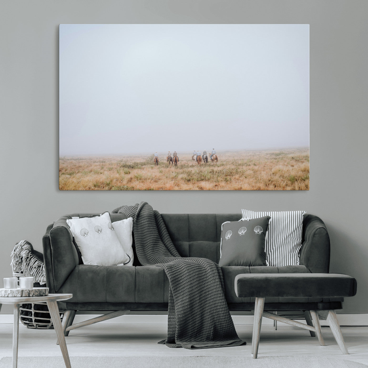 A group of horseback riders moving through a fog-shrouded field, evoking a calm Western scene with golden grasses and soft horizons.