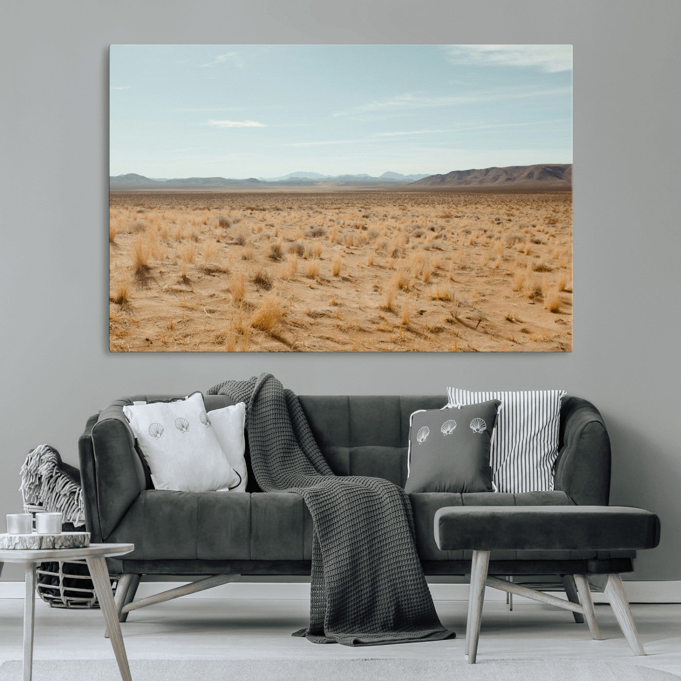 Expansive desert landscape with scattered dry grass and distant mountain range under a pale blue sky – Wall Art Canvas Print.