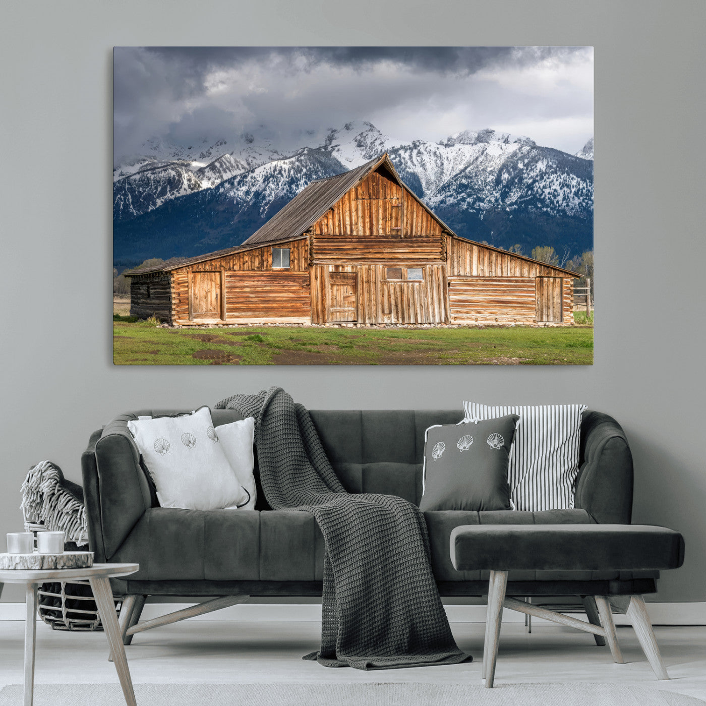 A stunning wall art canvas print featuring a rustic wooden barn set against a backdrop of snow-capped mountains under a dramatic cloudy sky, perfect for adding a touch of rural charm to any space.