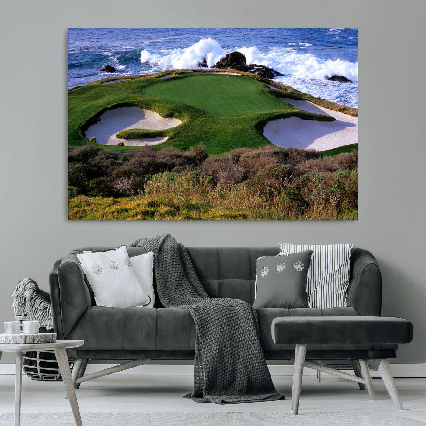 A scenic golf course located by the ocean, featuring a well-manicured green surrounded by sand traps and powerful ocean waves crashing on the shore.