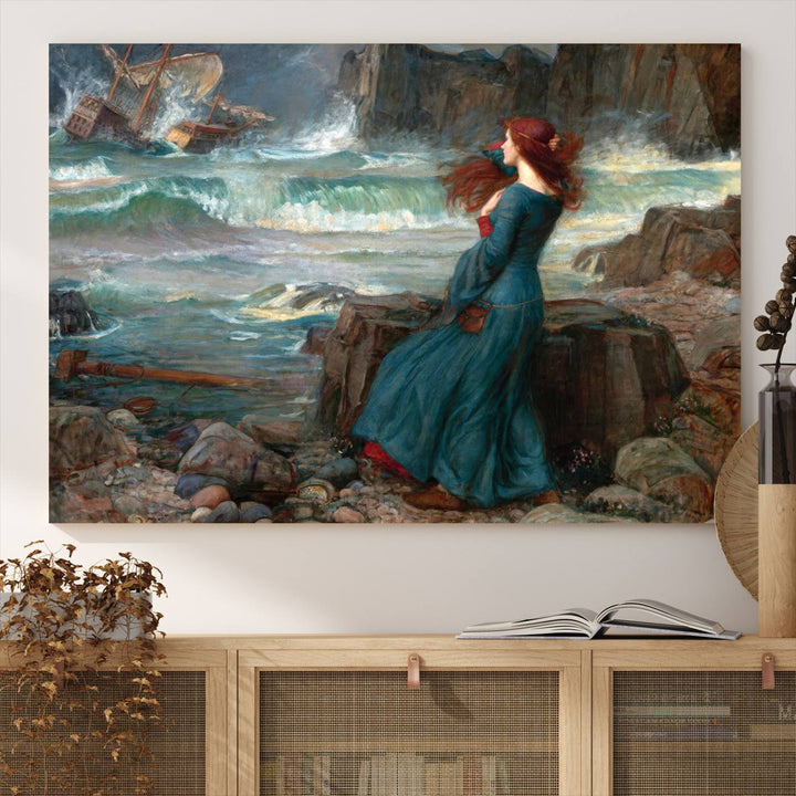 The Miranda by the Shore Wall Art Canvas Print depicts a woman in a blue dress standing by the sea, watching a shipwreck.