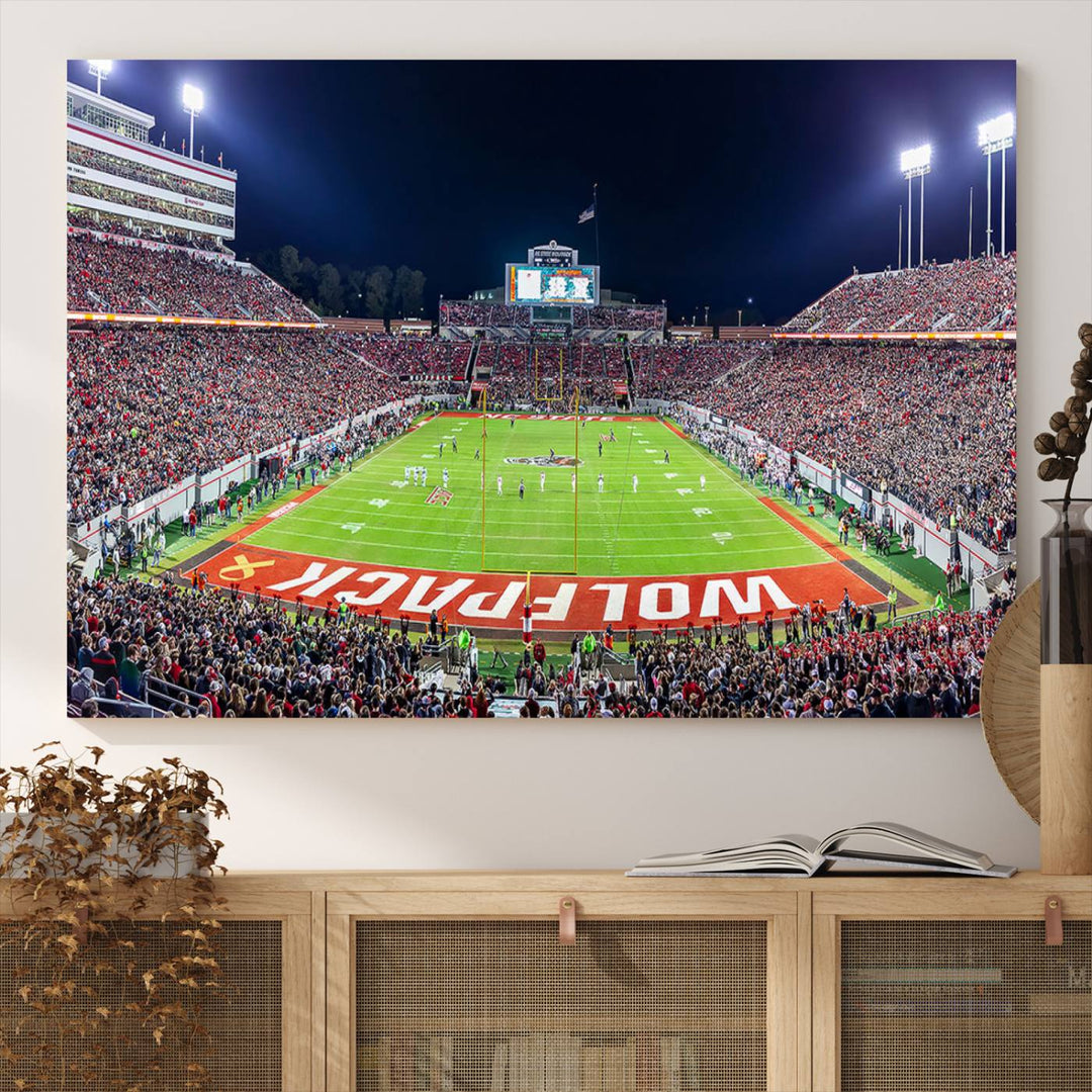 A NC State Wolfpack Football Team print of Carter-Finley Stadium at night features WOLFPACK illuminated brightly in the end zone grass.