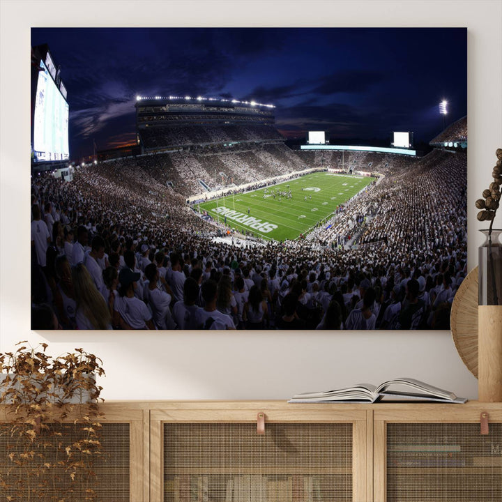 A packed football stadium at night, with bright lights and fans in white, depicted in a Michigan State Spartans Stadium wall art.