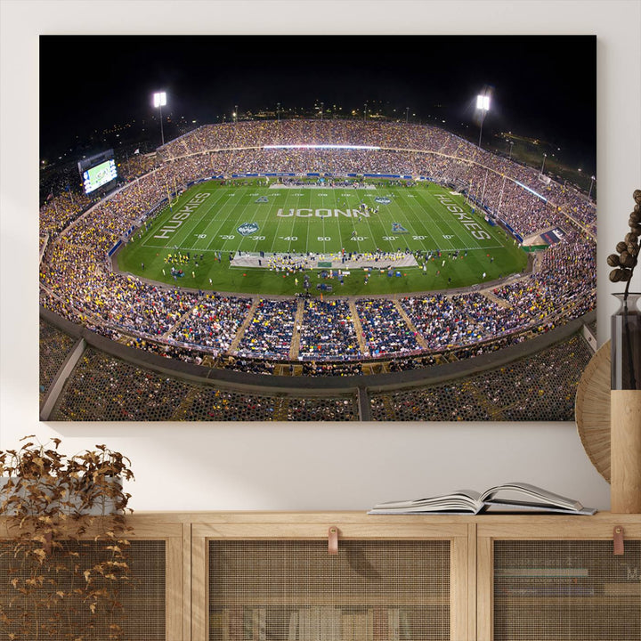 A large football stadium at night, featuring the UCONN Huskies, is depicted on the East Hartford Pratt & Whitney Stadium Wall Art Canvas Print.