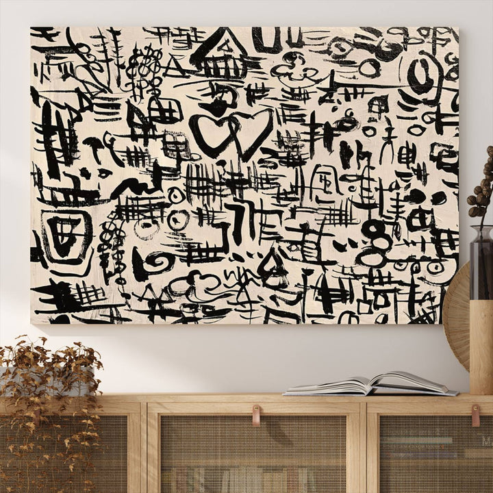 The Abstract Love and Chaos canvas is a museum-quality print featuring black symbols on a beige background, adorned with a heart and scribble design. It is framed to enhance its artistic appeal.