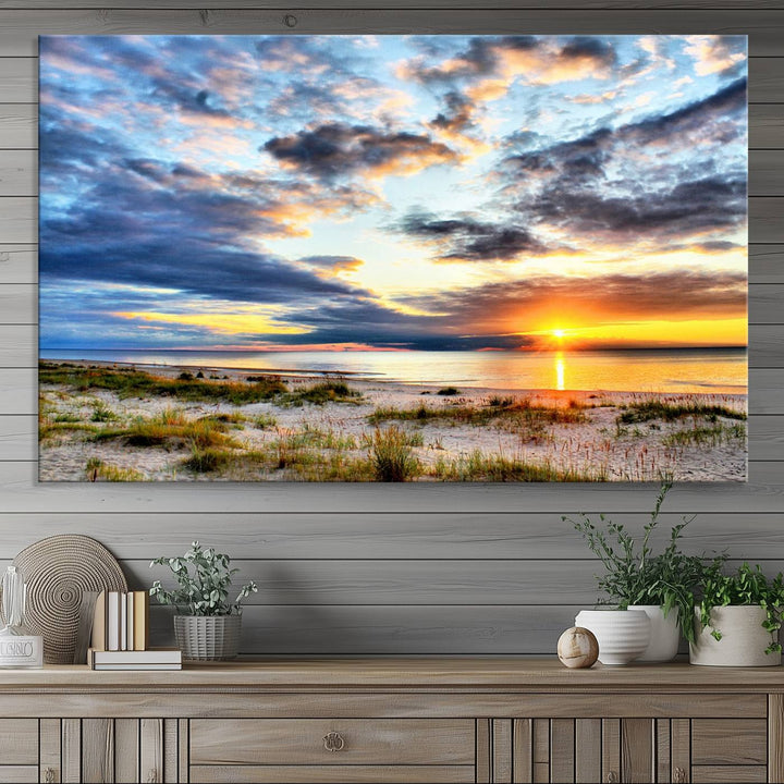 The Sunset On The Ocean canvas wall art features a beautiful beach sunset with grass and clouds.