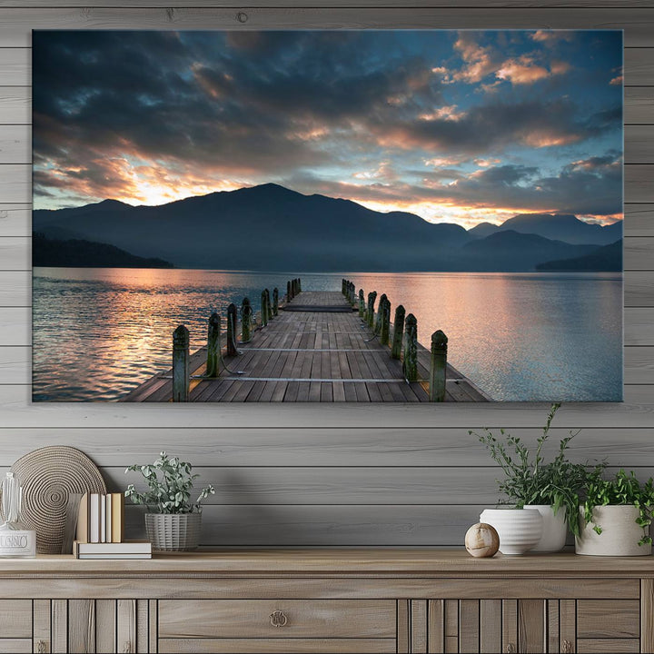 The Mountain Lake Wood Pier Canvas Wall Art depicts a serene lake and mountains, enhancing the beauty of any space.