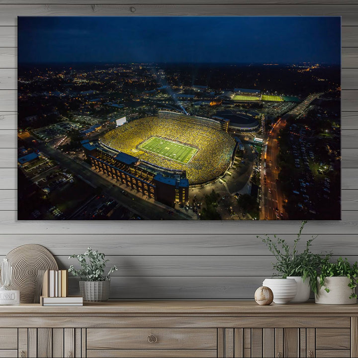 Aerial view of Michigan Stadium at night, surrounded by city lights, depicted on a Michigan Wolverines wall art canvas print.