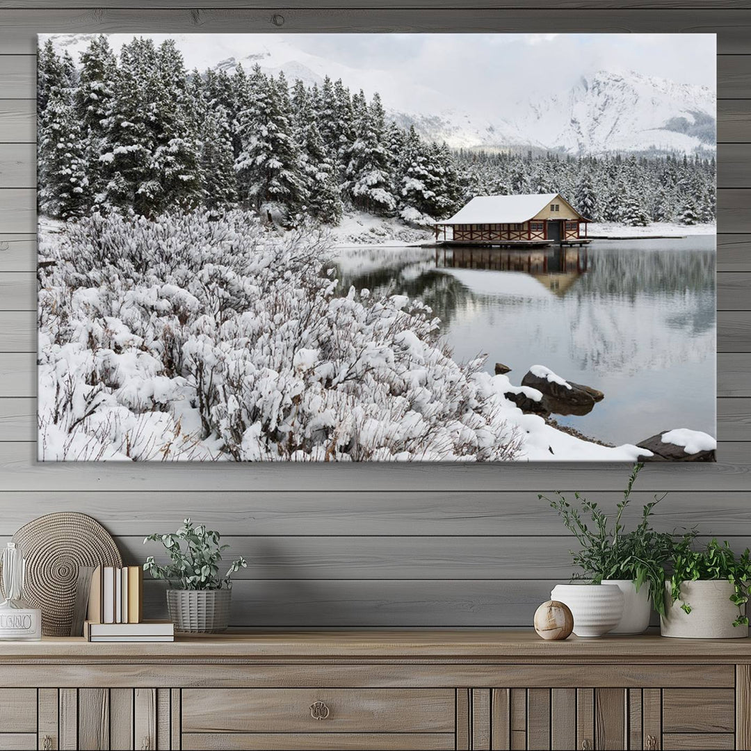 Experience the beauty of winter with the "Cabin by the Lake Canvas Wall Art," showcasing a serene snowy landscape. This rustic nature decor features a cozy cabin nestled amid snow-laden trees, set against a breathtaking mountain view, perfect for enhancing your living room.