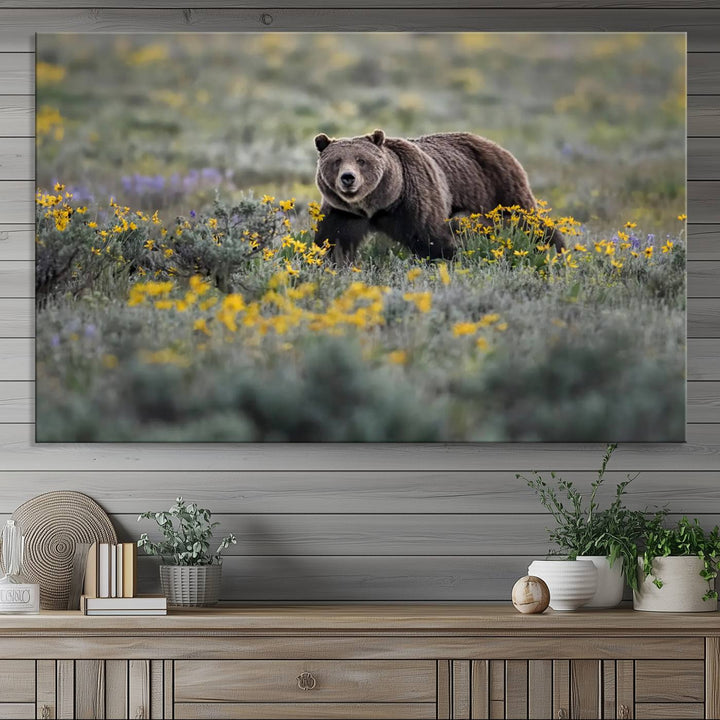 The "Grizzly 399 in Wild Flowers Wall Art Canvas Print" features a grizzly bear strolling through a field of yellow and purple flowers, beautifully showcased as a triptych. This handcrafted piece, proudly made in the USA, adds charm and sophistication to your space.