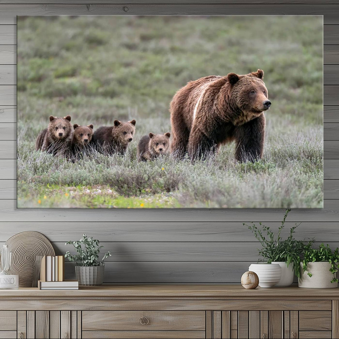 The large canvas print titled "Queen of the Tetons, 399 Grizzly Bear Cubs" showcases majestic wildlife photography of a bear and her cubs walking through the grass. This stunning canvas wall art, handmade in the USA, adds a charming touch to any room with its rustic decor appeal.