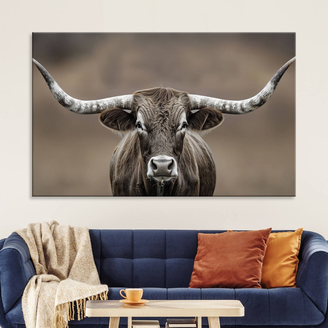 A close-up of a longhorn bull facing forward is featured in the Framed Texas Test-1, set against a blurred brown background.