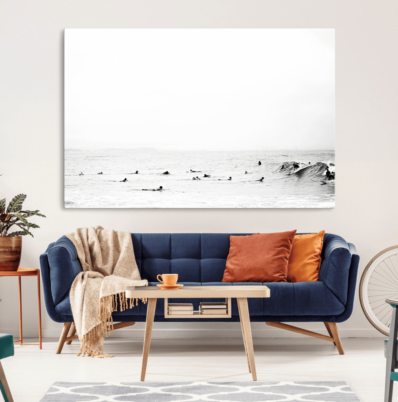 A group of surfers floating in the ocean, waiting for waves under a vast, moody sky, captured in black and white.