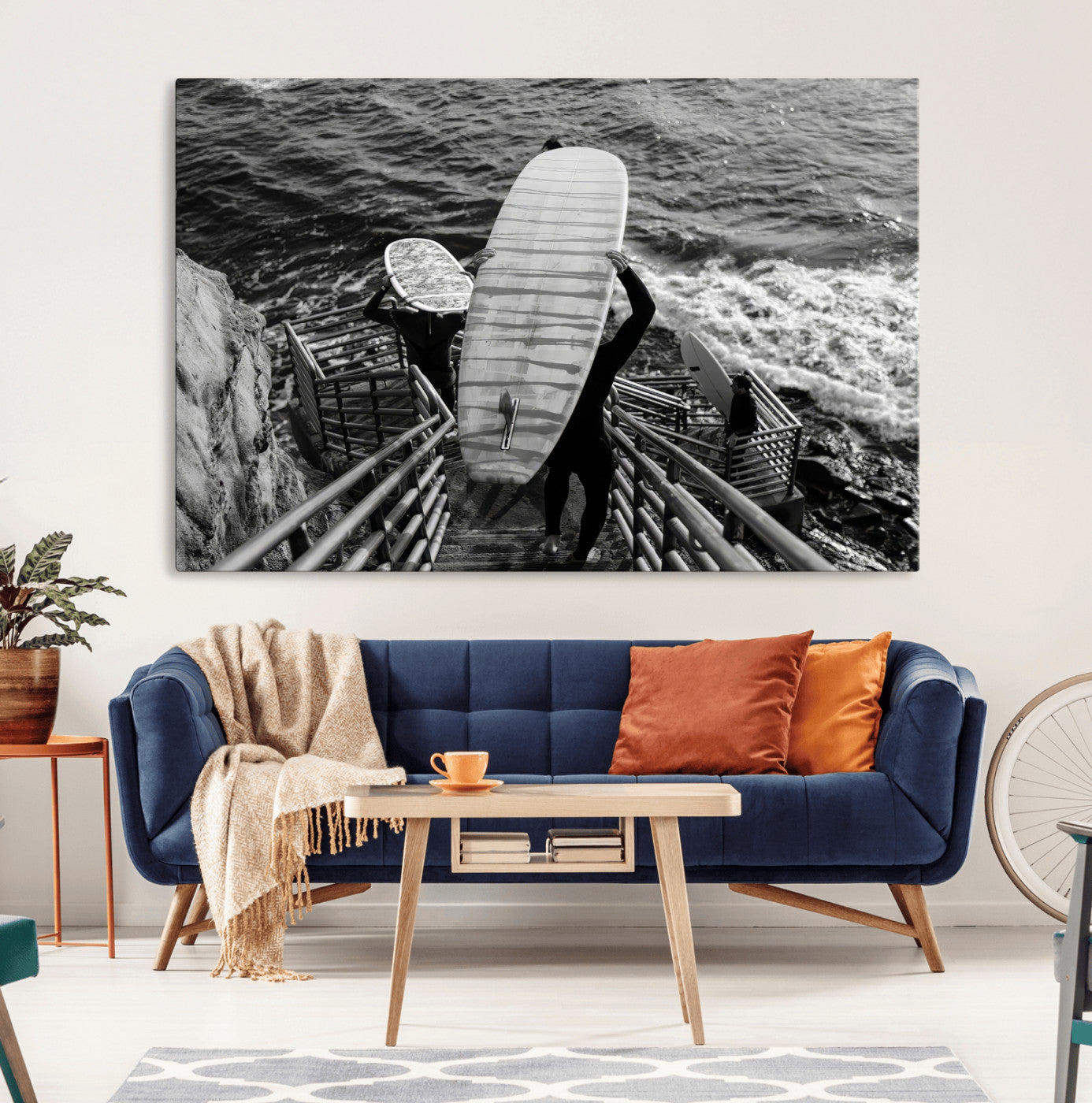 Black and white photo of surfers carrying boards down a rugged cliffside stairway, capturing a bold and adventurous coastal scene.