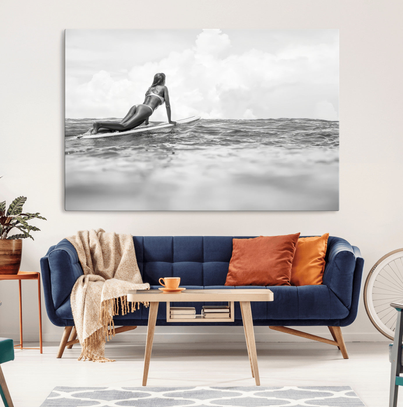 A black and white ocean scene featuring a surfer girl waiting on her board, gazing at the horizon, capturing a tranquil and adventurous coastal moment.