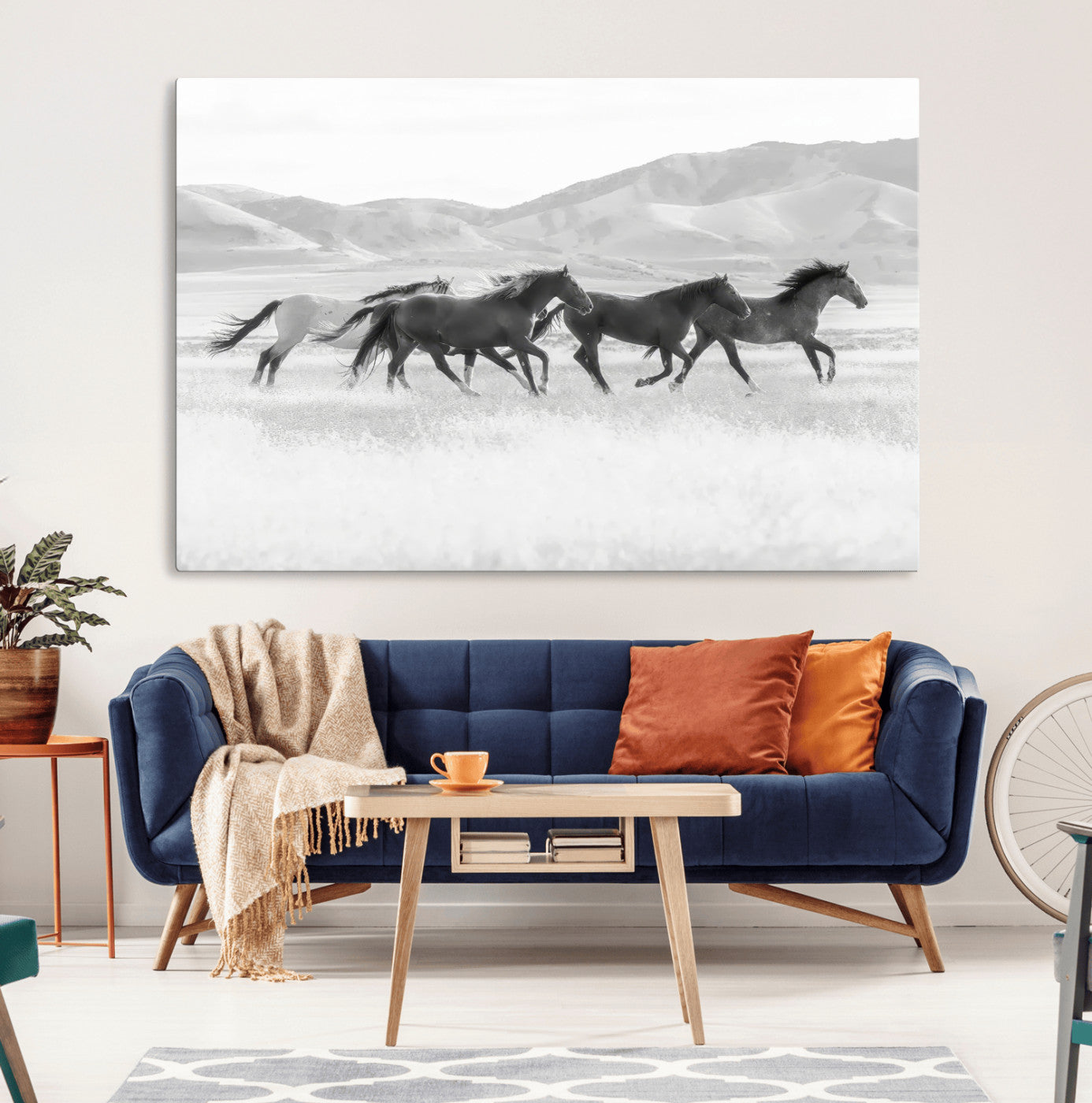 A black and white image of wild horses running freely across an open grassland, capturing the power and beauty of untamed nature in a rustic western setting.