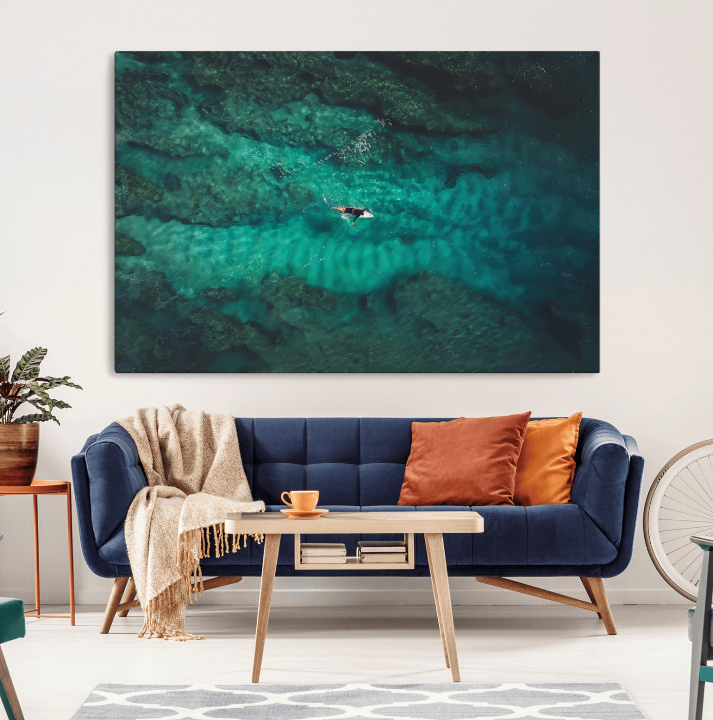 An aerial view of a solo surfer paddling through crystal-clear turquoise waters over a sunlit reef, capturing the beauty and serenity of open water surfing.