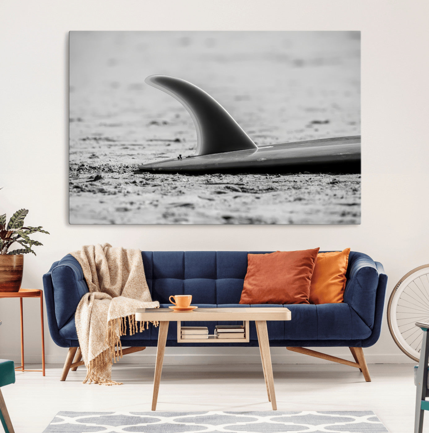 A black and white close-up of a surfboard fin resting on the sandy shore, highlighting minimalist beach aesthetics and classic surf culture.