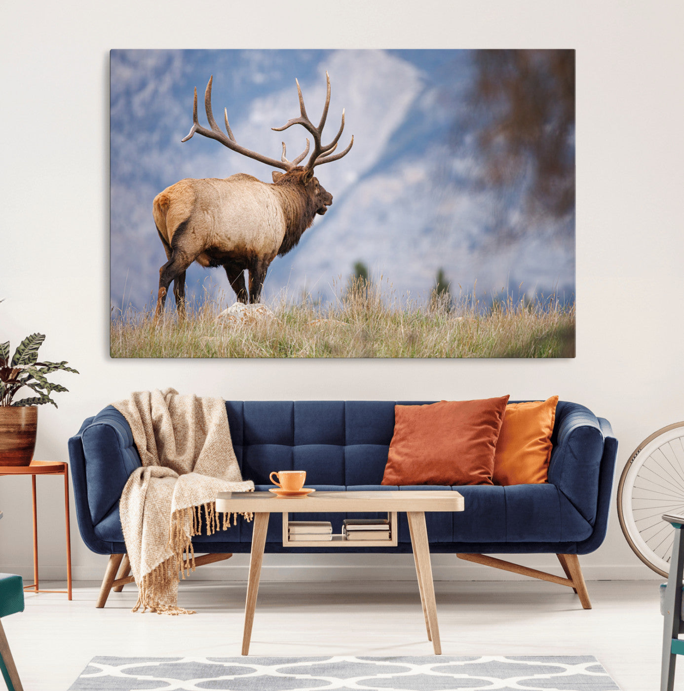 Elk with antlers standing on grass with mountain background, ideal for rustic, cabin, or lodge-inspired wall decor.