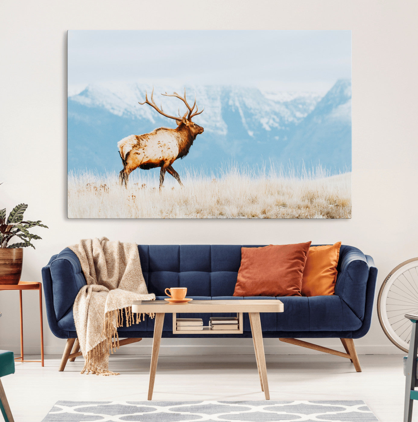 Majestic elk standing on dry grassland with snowy mountains in the background, ideal for rustic or lodge-inspired wall decor.