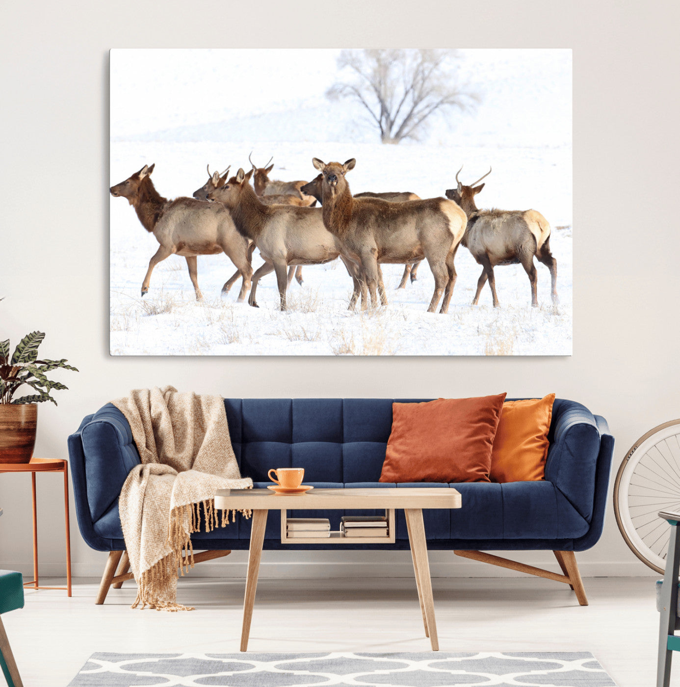 A group of elk standing on snowy terrain with a tree in the background, perfect for rustic or lodge-style winter wall decor.