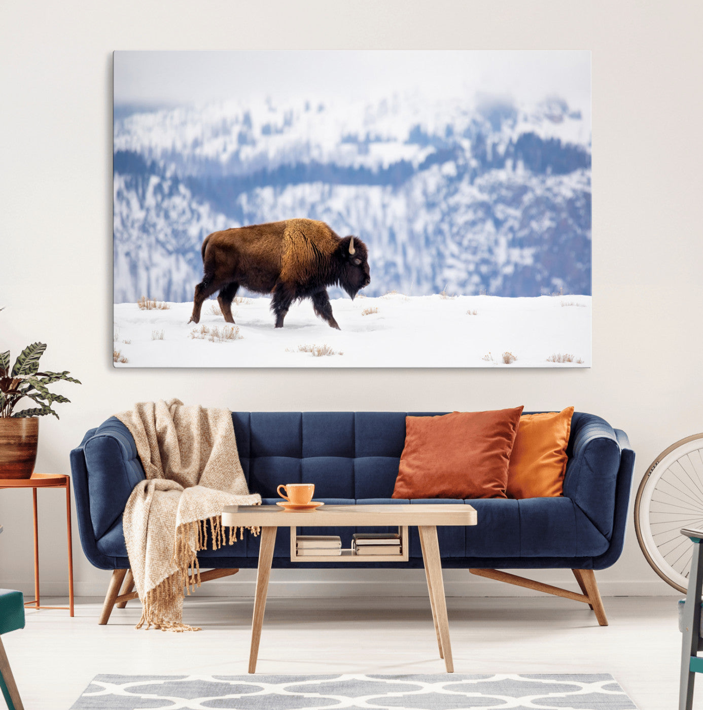 A lone bison walks across snowy ground with blue-toned mountain range behind, ideal for rustic or western farmhouse interiors.