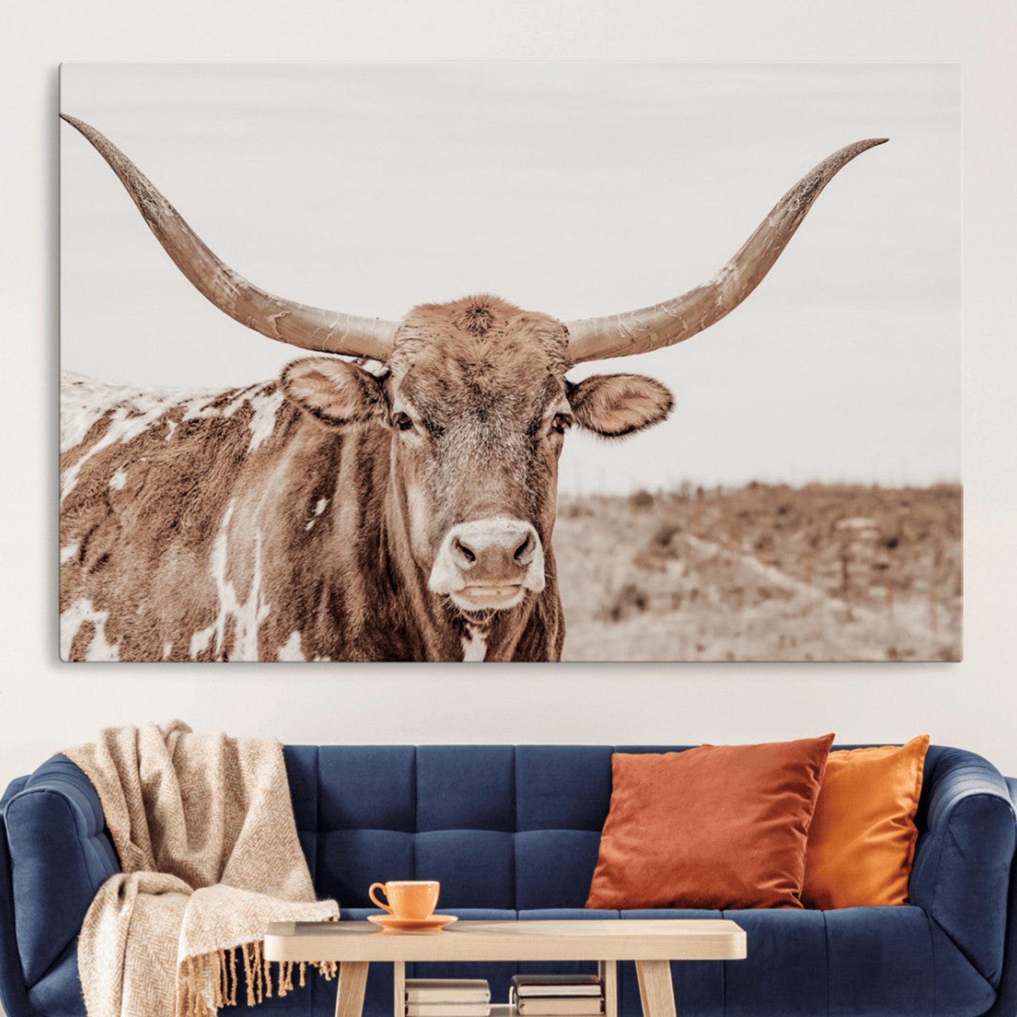 A longhorn cow in soft beige desert tones, standing calmly in open land, perfect for neutral western or rustic farmhouse interiors.