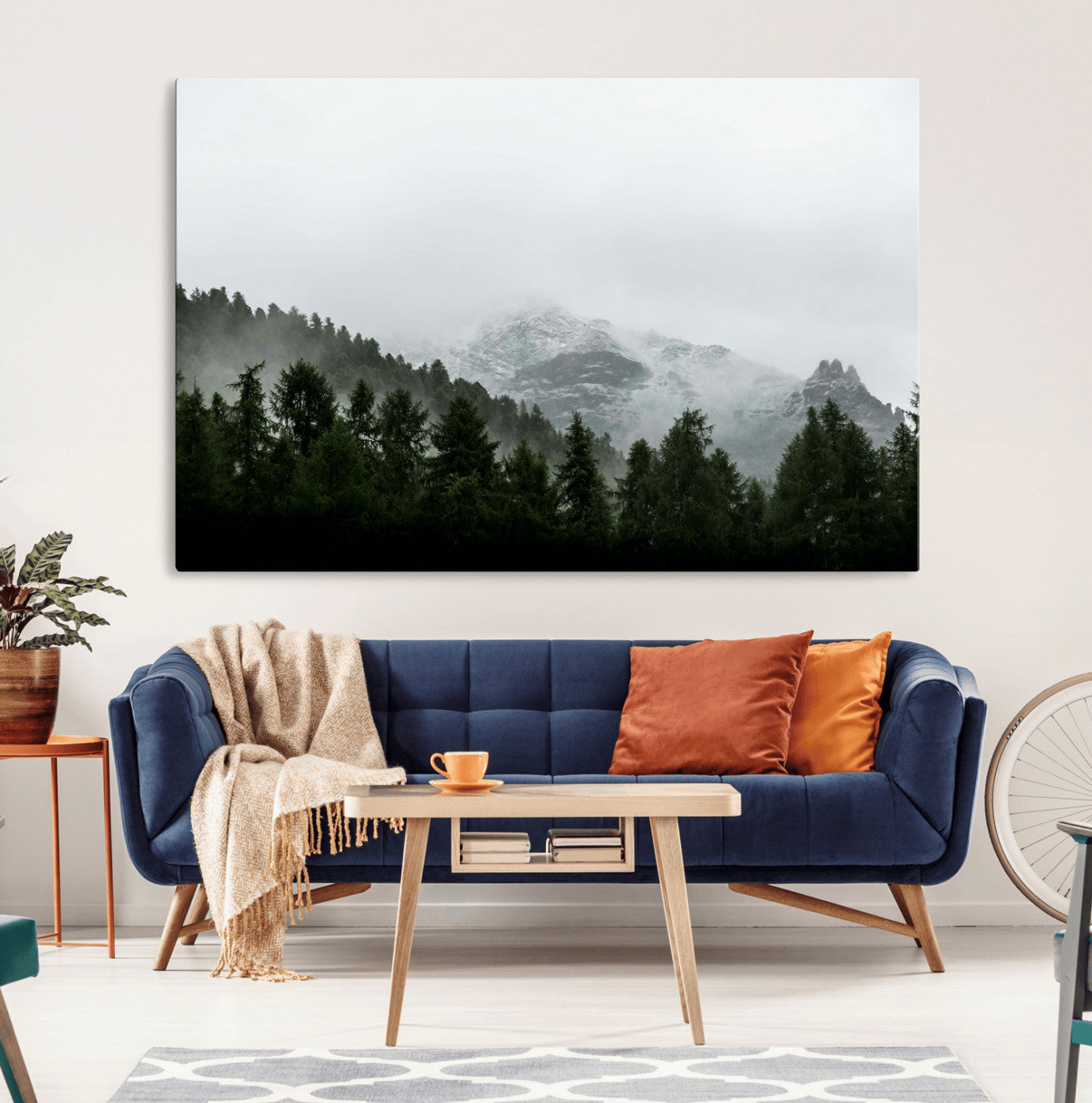 Snow-covered mountains emerging from a misty evergreen forest, creating a tranquil and moody wilderness landscape.
