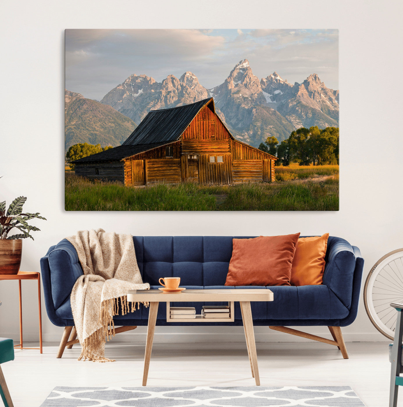Rustic wooden barn set against towering mountain peaks under warm golden light, creating a peaceful Western countryside scene.