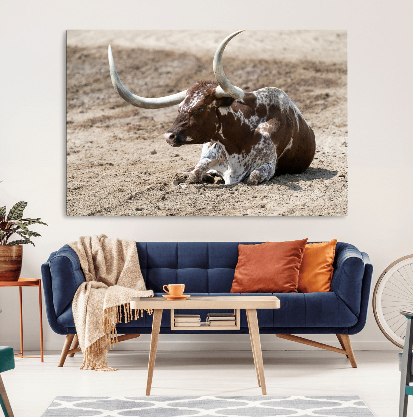 Texas Longhorn resting on sandy ground with large curved horns, capturing a rustic Western aesthetic perfect for farmhouse-style wall art.