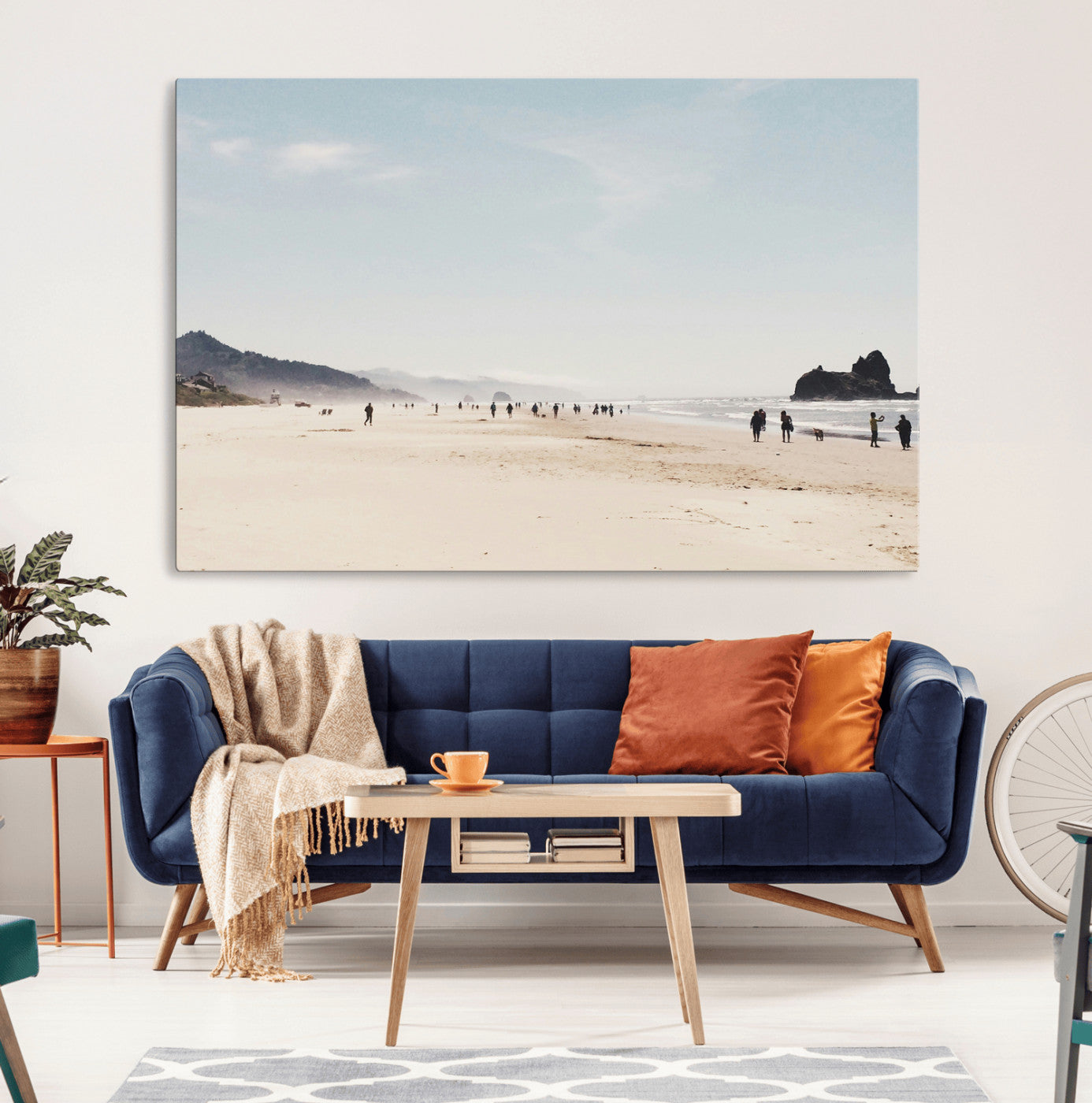 A serene beach with soft sand, misty mountains, and scattered people walking along the shoreline, creating a peaceful coastal landscape.