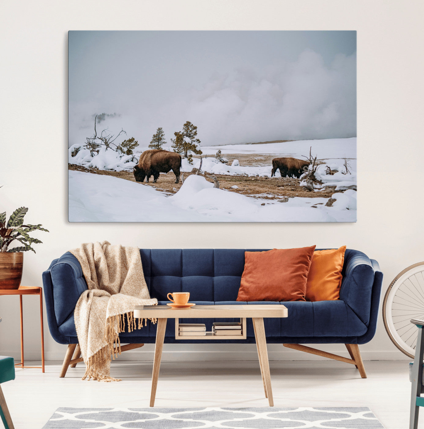 Two bison grazing in a snowy open landscape with misty hills in the background, creating a peaceful and rustic winter scene.