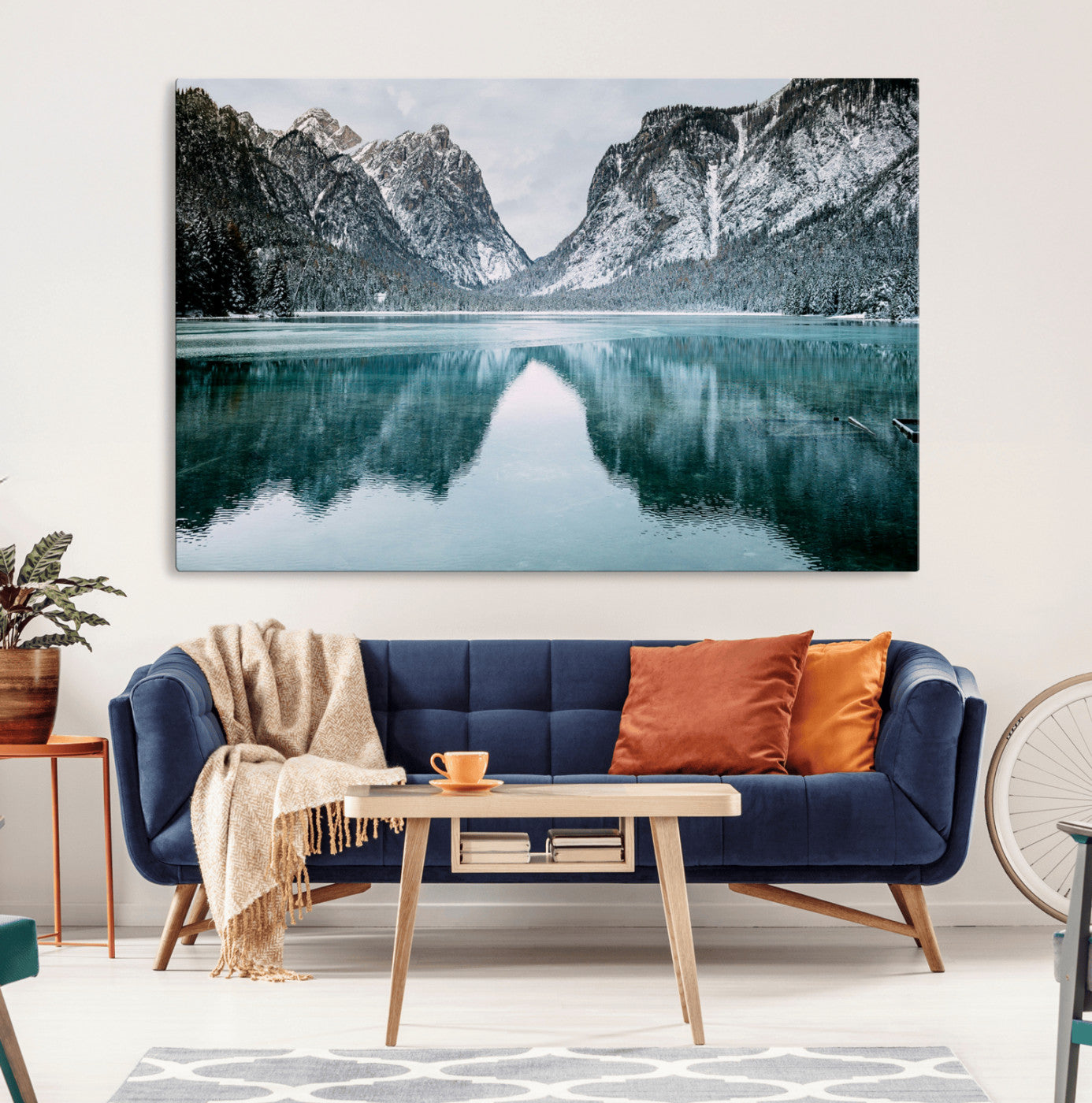 Crystal-clear alpine lake reflecting snow-covered mountains, surrounded by evergreen trees, creating a serene and tranquil winter landscape.