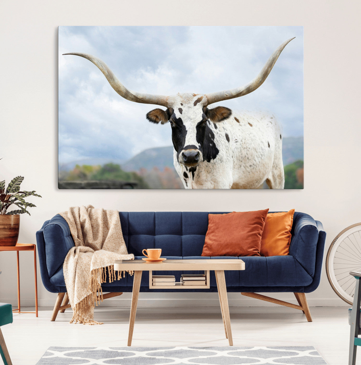 Close-up of a Texas Longhorn with curved horns, black and white markings, set against a cloudy sky and distant hills, perfect for rustic decor.