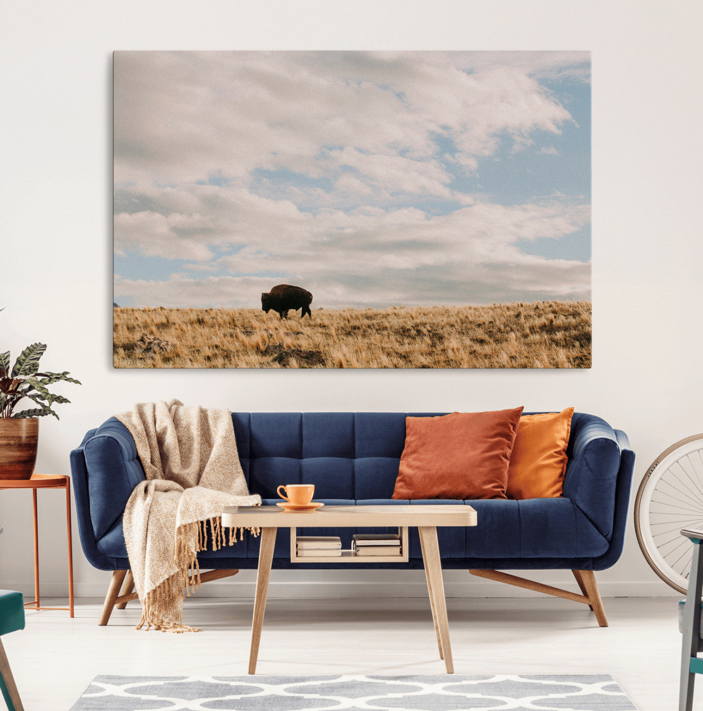 A solitary bison walking across a golden prairie under a vast, cloud-filled sky, evoking a peaceful, rustic western landscape for home decor.