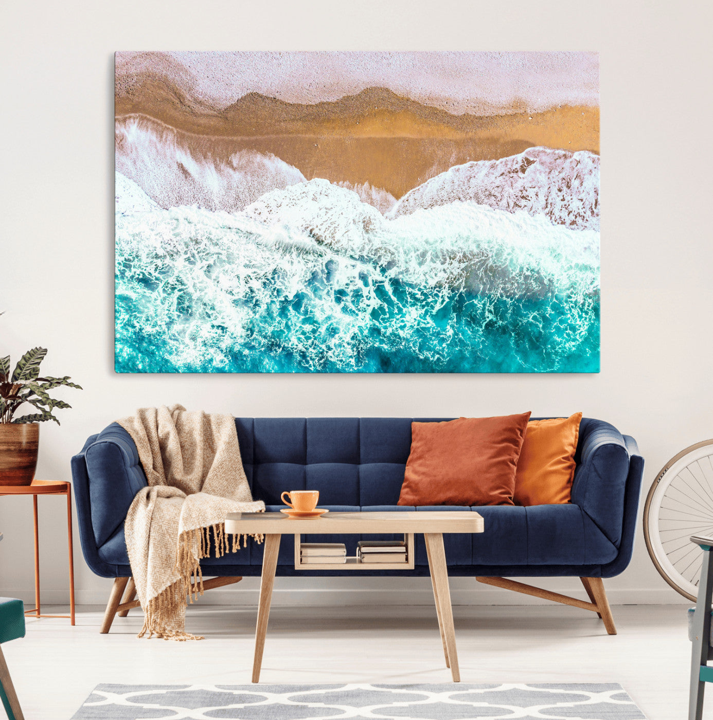 Aerial view of ocean waves crashing onto a sandy beach, with turquoise water and foamy white surf, creating a serene coastal aesthetic for home decor.