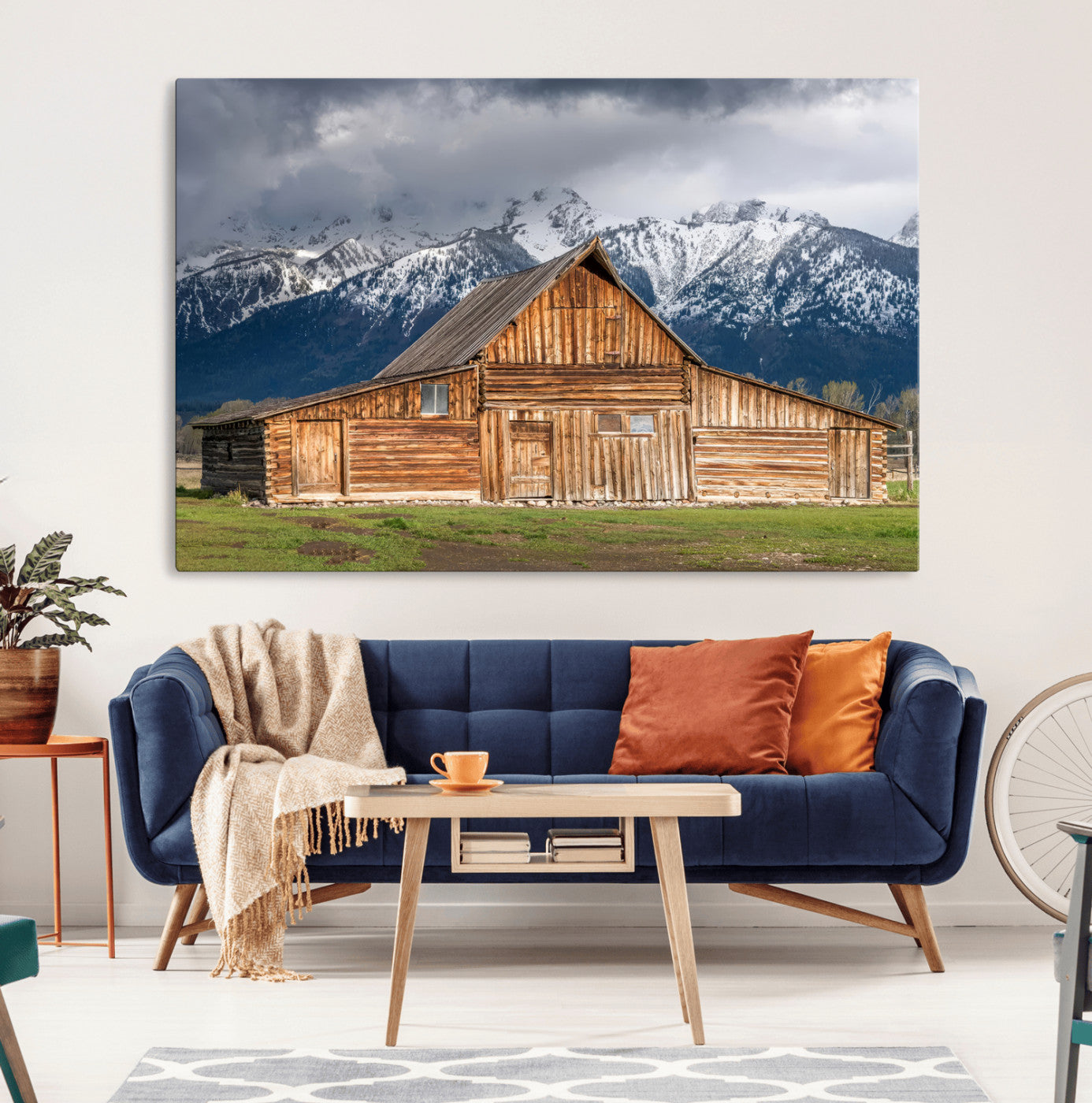A stunning wall art canvas print featuring a rustic wooden barn set against a backdrop of snow-capped mountains under a dramatic cloudy sky, perfect for adding a touch of rural charm to any space.
