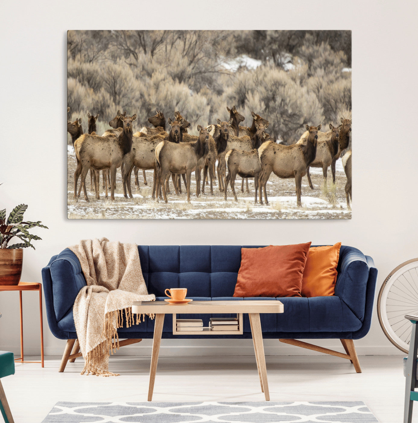 A stunning wall art canvas print featuring a large herd of elk standing together in a natural winter landscape with muted earthy tones and soft background foliage, perfect for rustic or nature-inspired home decor.