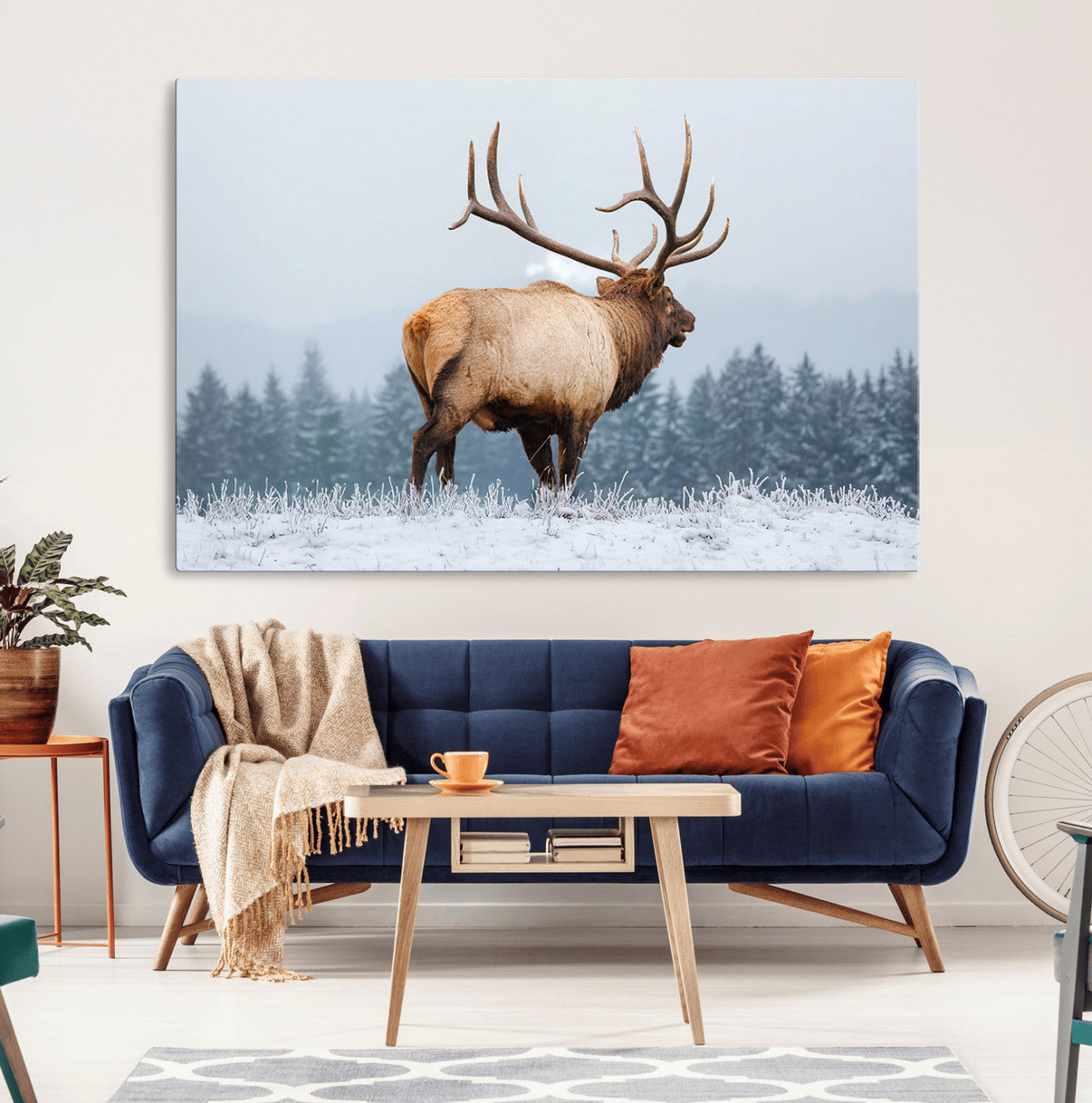 A majestic elk standing in a snowy landscape, with large antlers, set against a backdrop of evergreen trees and a soft winter sky.