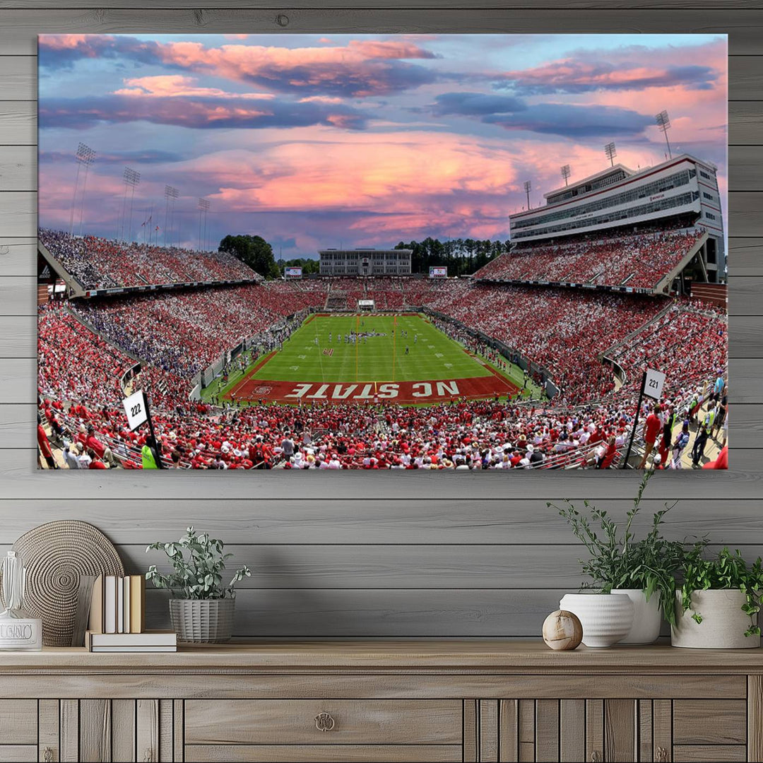 The wall art captures an NC State Wolfpack game under a vibrant sunset on triple canvas.