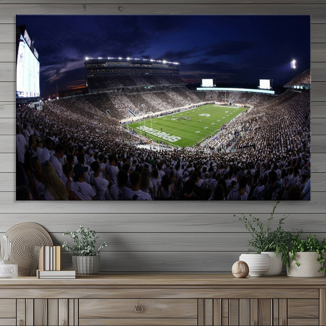 A packed football stadium at night, with bright lights and fans in white, depicted in a Michigan State Spartans Stadium wall art.