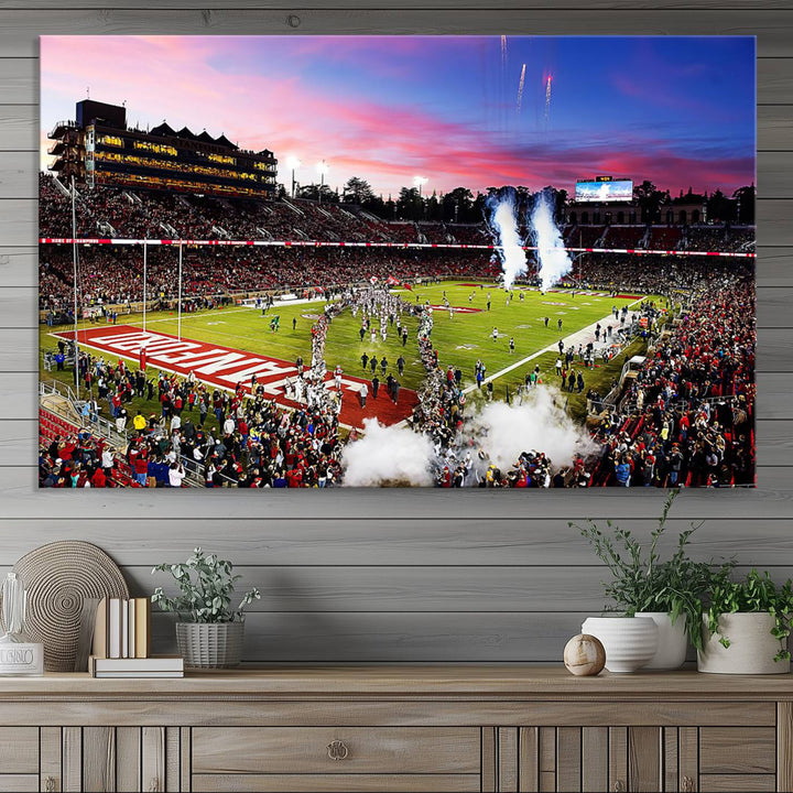 The wall art features a canvas print of the Stanford Cardinal football team, capturing players, fireworks, and smoke against the backdrop of a sunset at Stanford Stadium.